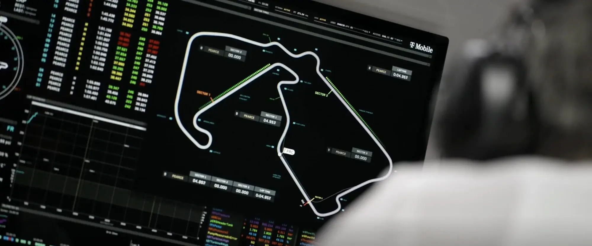Still from F1 (2025): a pit wall screen showing the whole Silverstone circuit as a white line, with floating sector time cards for the driver Pearce, dotted green overlays along the straights, a lap time column on the left and a split table below